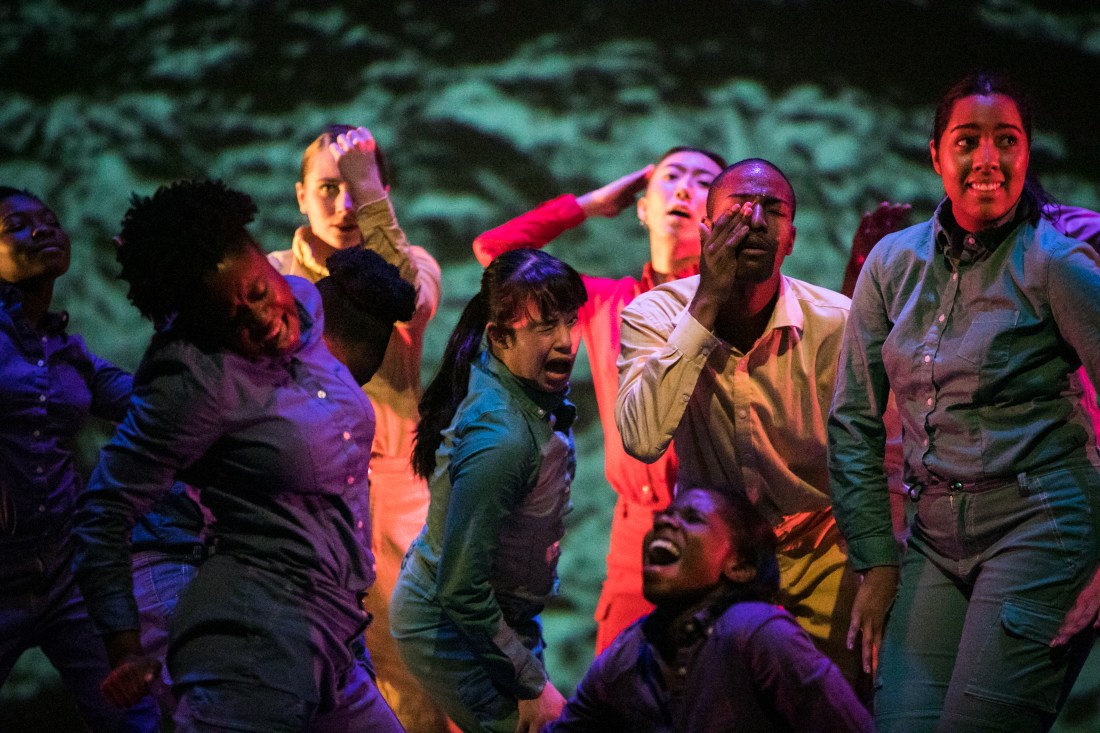 A group of seven people, each wearing a different colored bodysuit.